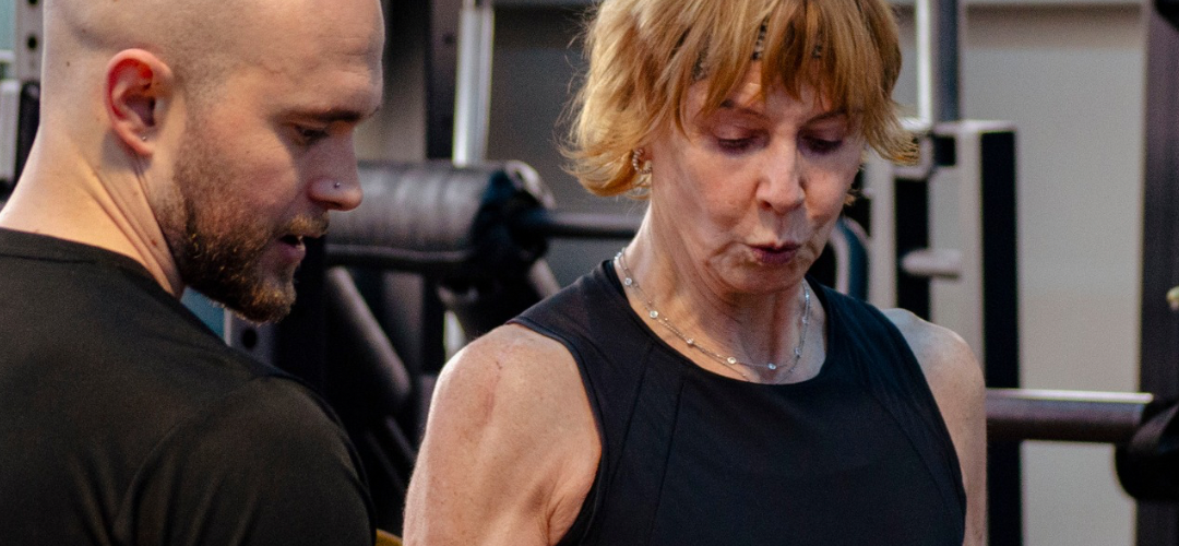 Person Training assisting middle aged lady with injury rehabilitation.