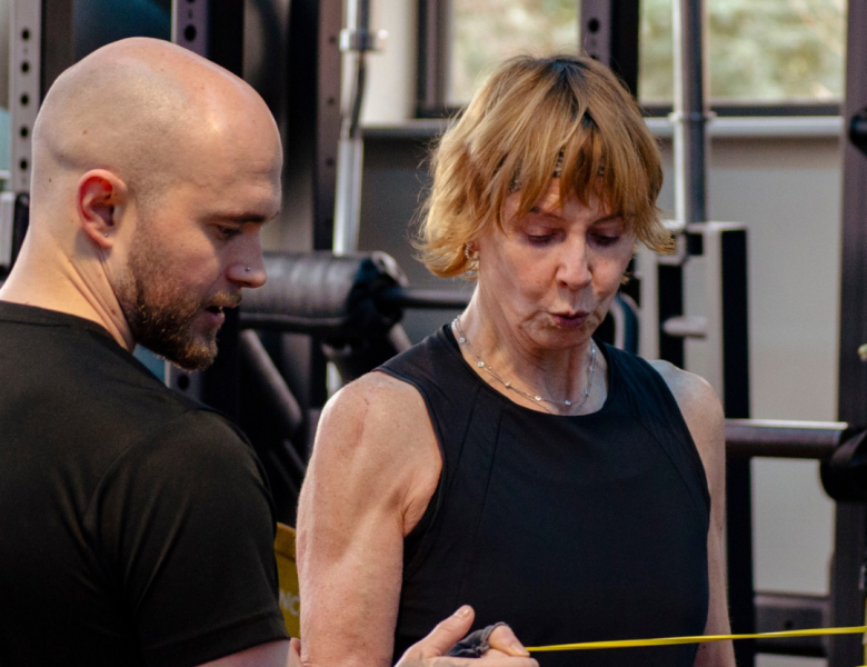 Person Training assisting middle aged lady with injury rehabilitation.